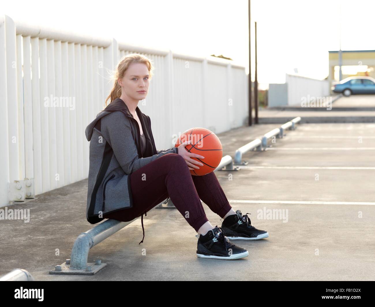 Junge weibliche Basketball-Spieler sitzen auf Parkplatz Stockfoto