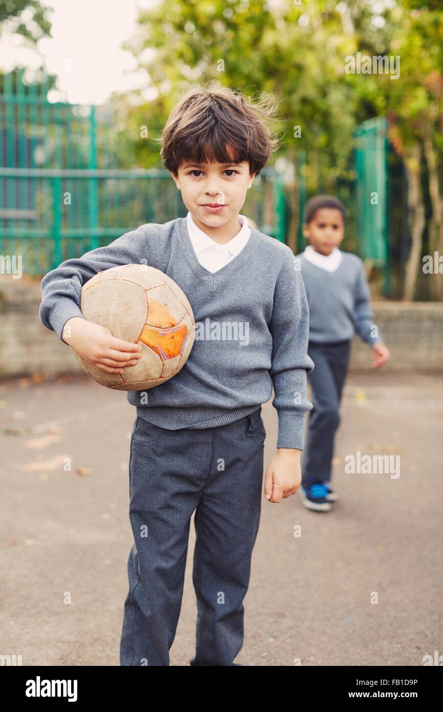 Porträt von elementaren Schuljunge mit Fußball Ball auf Spielplatz Stockfoto