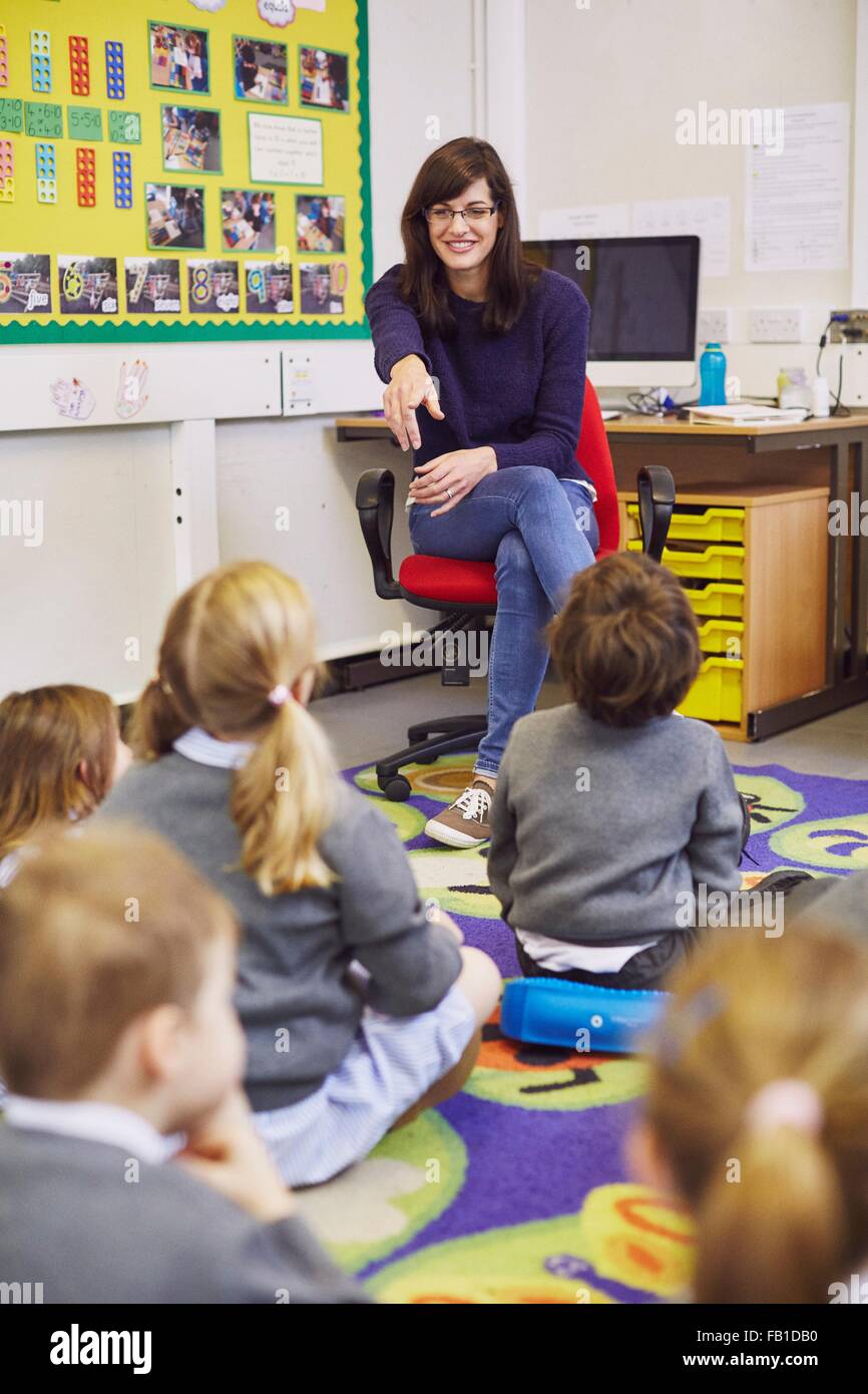 Lehrer auf Kinder sitzen am Boden im Unterricht der Grundschule Stockfoto