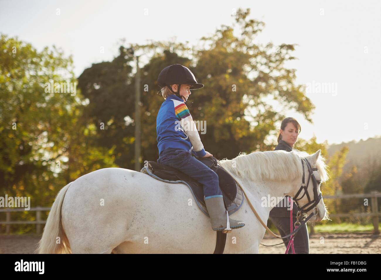 Kursleiter führende junge Reiten Pony im Pferdesport-arena Stockfoto