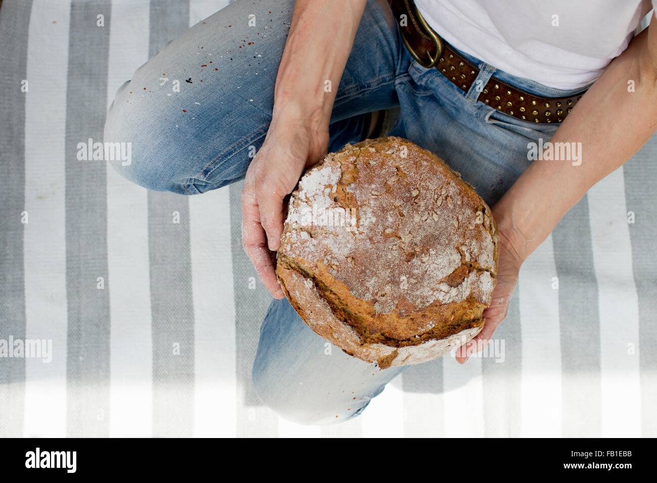 Draufsicht der Reife Frau auf gestreiften Teppich halten frisches gebackenes Brot Stockfoto