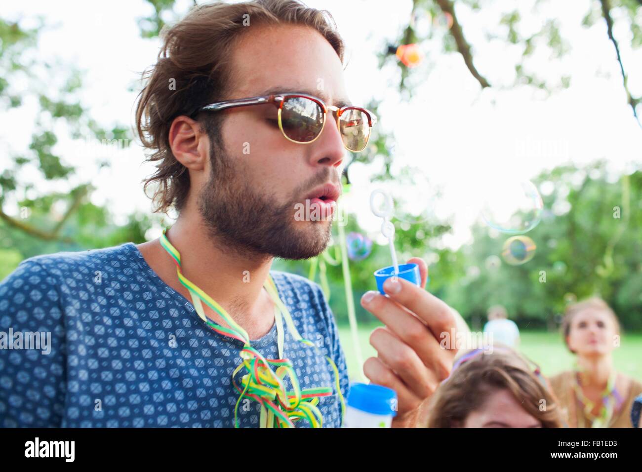 Junger Mann bläst Seifenblasen auf sunset Party im park Stockfoto