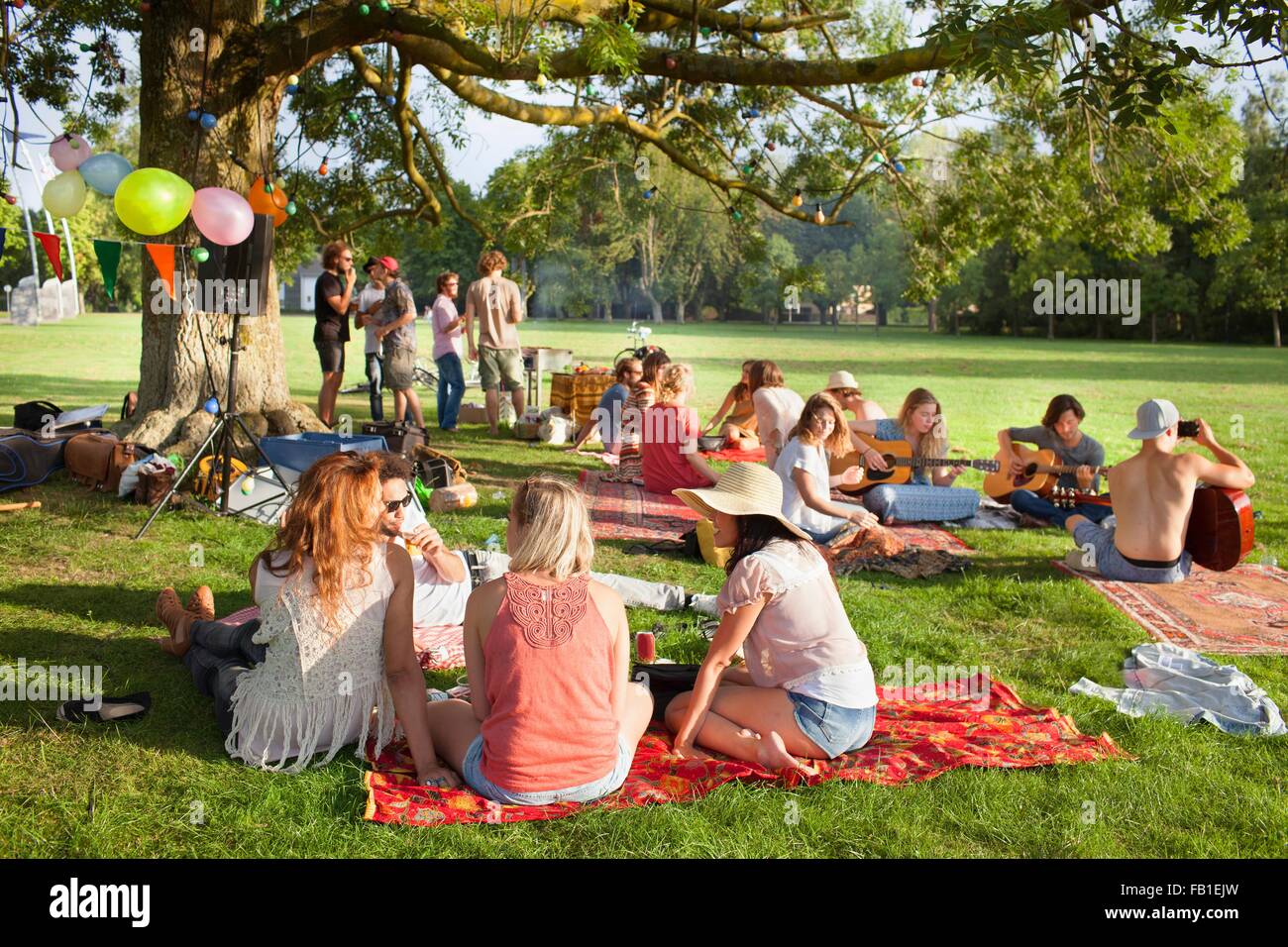 Gruppe von Freunden anhören von Musik unter Parkbaum auf sunset party Stockfoto