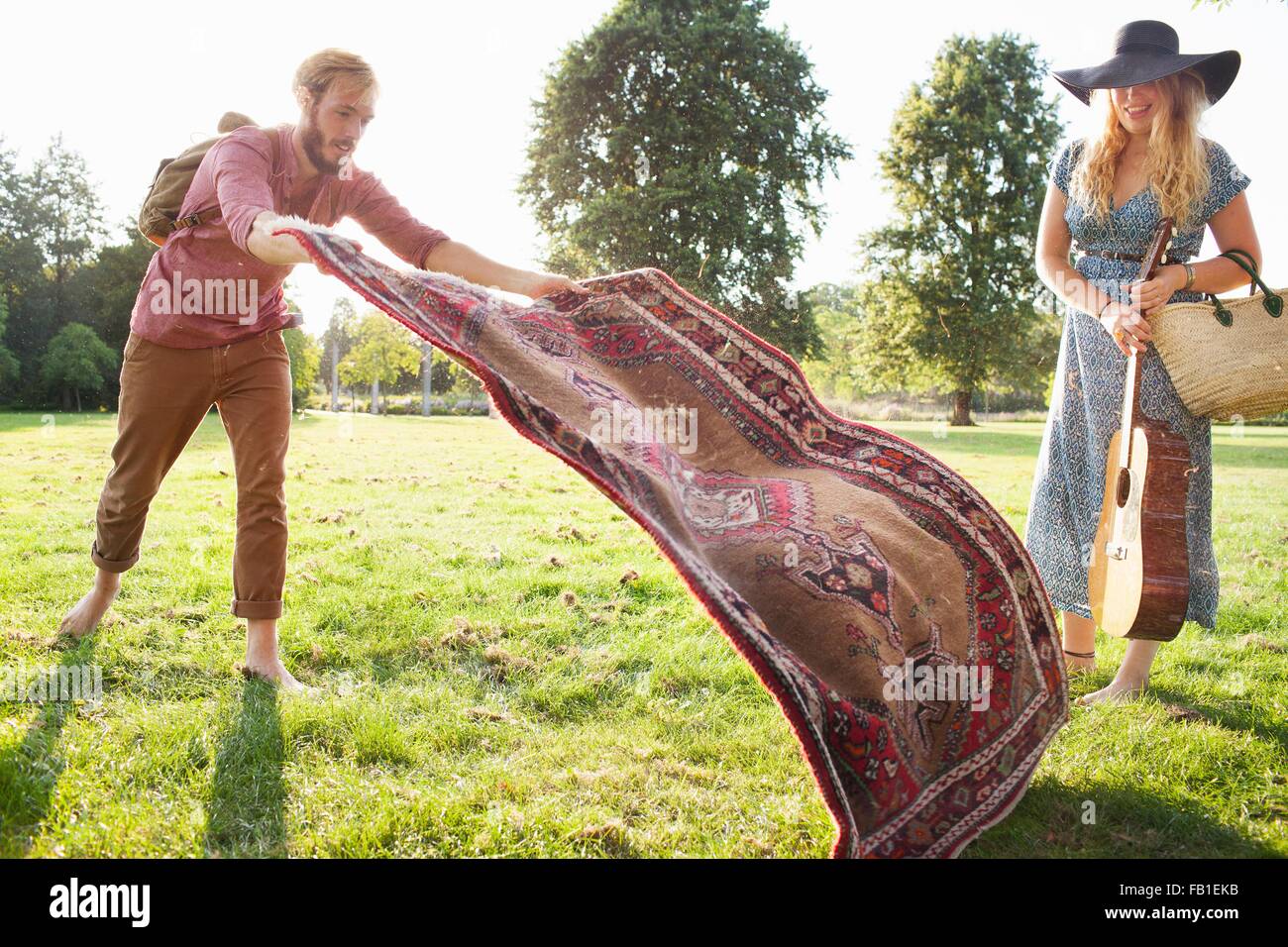 Romantische junges Paar ausbreitenden Teppich für Picknick im park Stockfoto