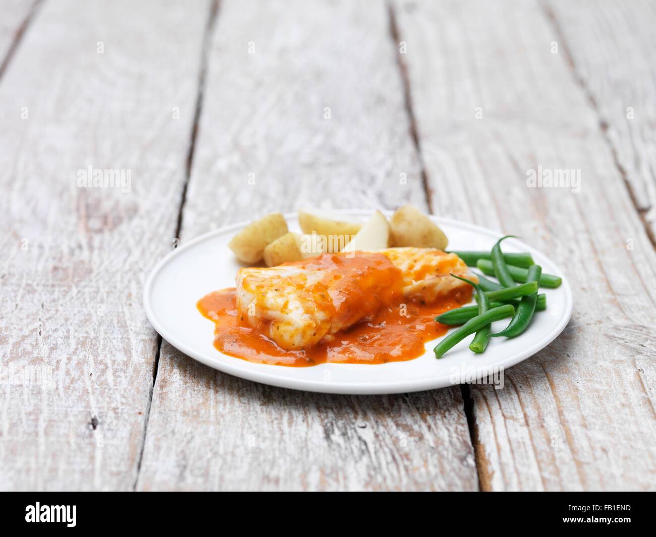 Kabeljau-Filets mit einer Tomaten-Kräuter-Sauce serviert mit grünen Bohnen und neuen Kartoffeln Stockfoto