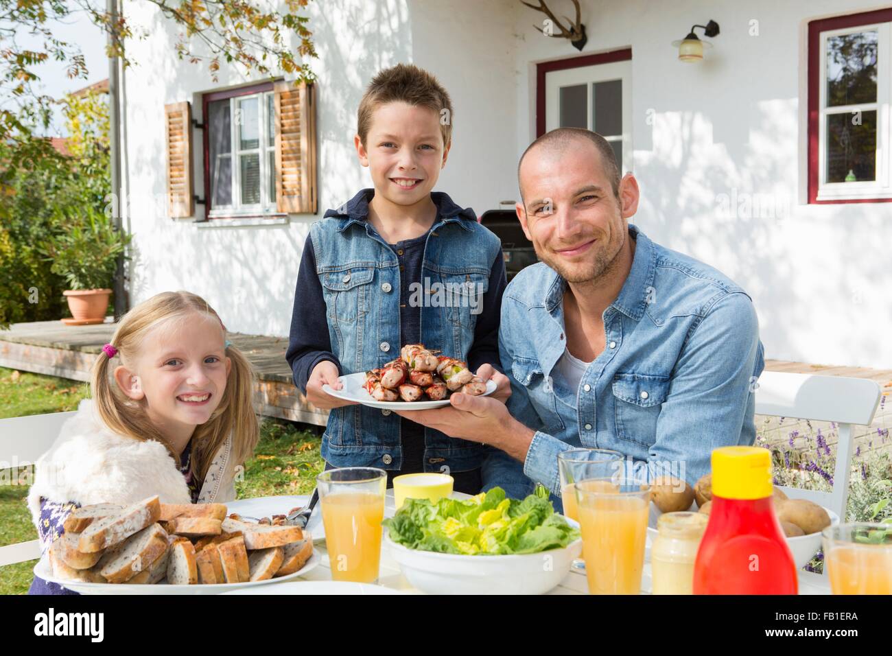 Porträt von Vater und Kindern am Grill im Garten Tisch Stockfoto