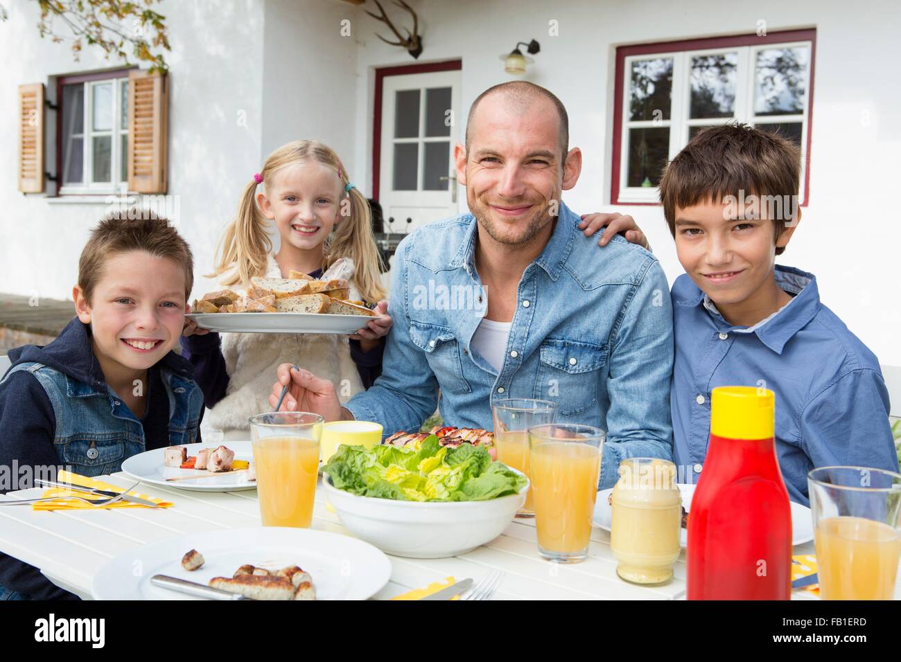 Porträt von Vater und seinen drei Kindern am Grill im Garten Tisch Stockfoto