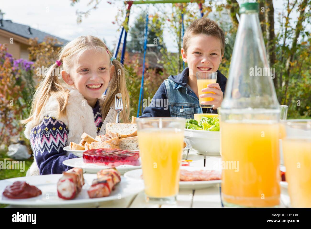 Schwester und Bruder Saft zu trinken, am Grill im Garten Tisch Stockfoto