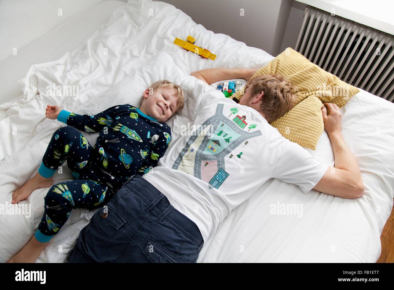 Kleiner Junge neben Vater n Bett liegend Stockfoto