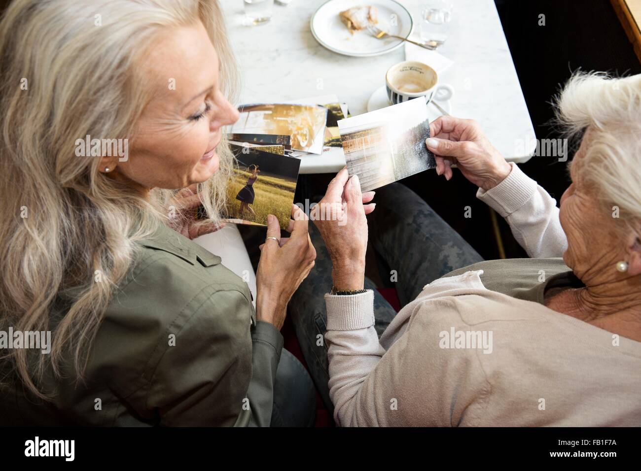 Mutter und Tochter beisammen sitzen im Café, Blick auf Fotografien, Rückansicht Stockfoto