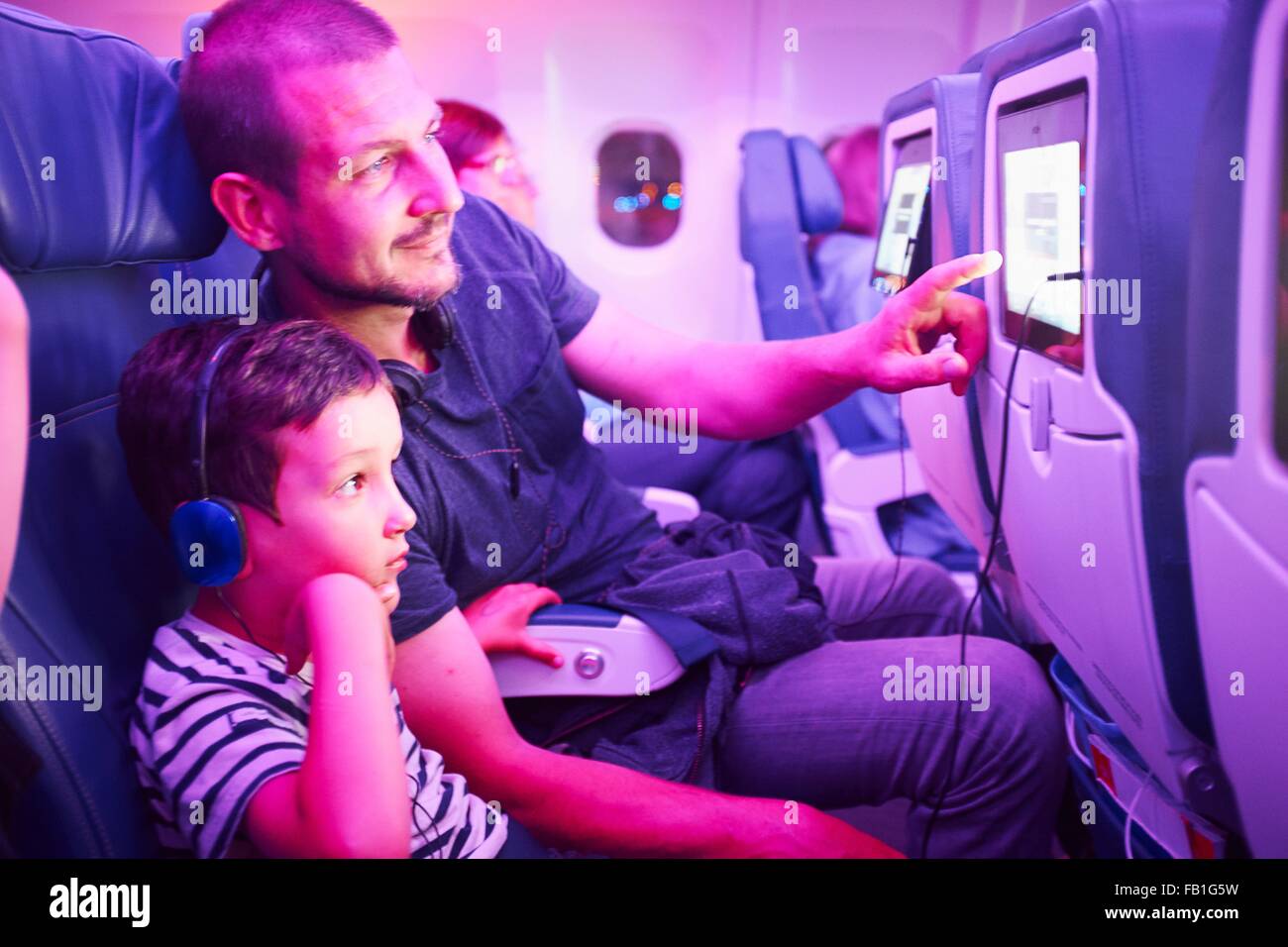 Vater und Sohn sitzen im Flugzeug, in-Flight-TV-Bildschirm betrachten Stockfoto