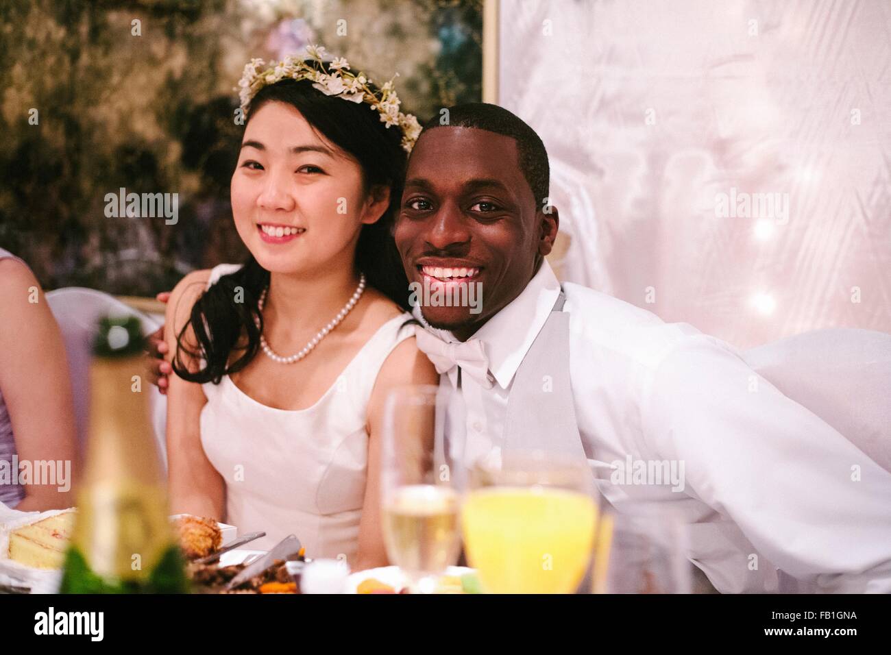 Braut und Bräutigam auf Hochzeit sitzen nebeneinander mit Blick auf die Kamera zu Lächeln Stockfoto