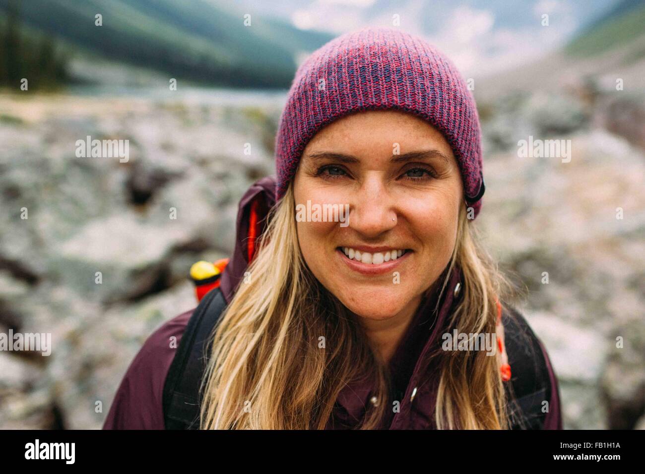 Porträt von Mitte erwachsenen Frau trägt stricken Hut Blick in die Kamera Lächeln, Moraine Lake, Banff Nationalpark, Alberta Kanada Stockfoto