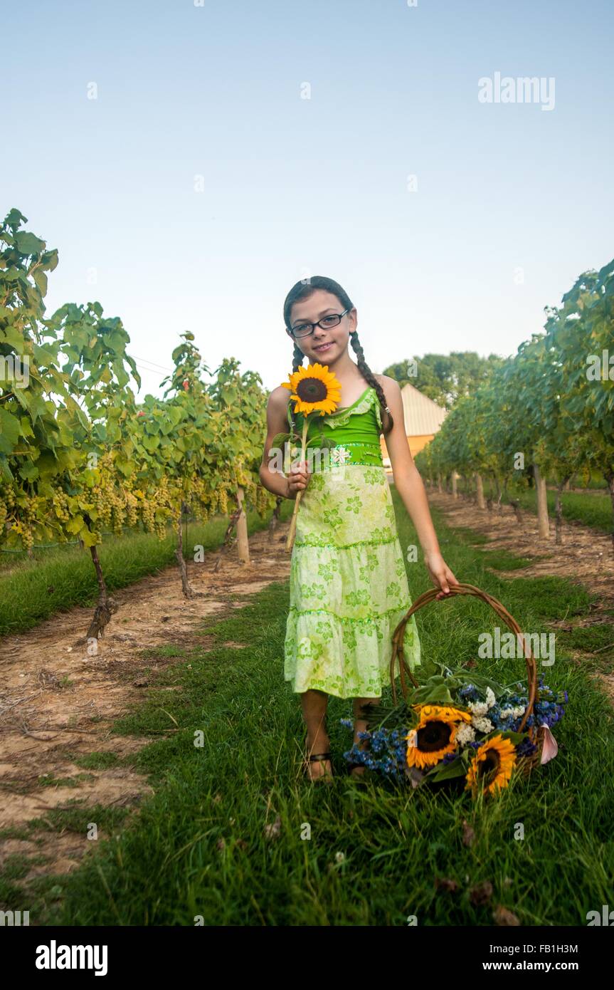 Porträt des jungen Mädchens mit Sonnenblume und Korb mit Blumen Stockfoto