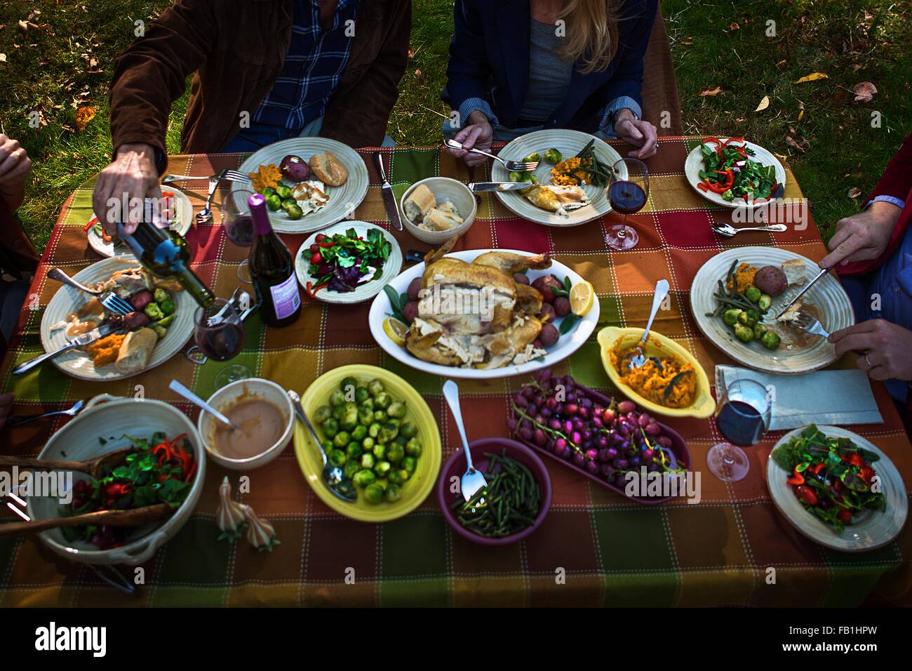 Aufnahme von zwei ältere Ehepaare Essen Braten Abendessen in Gartenparty beschnitten Stockfoto
