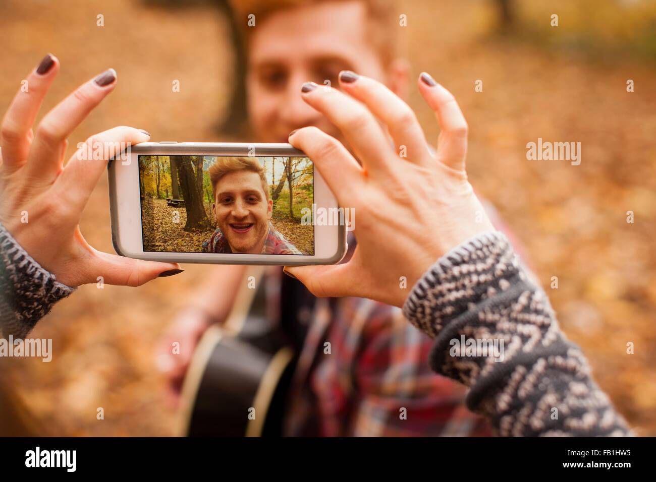 Hände der jungen Frau fotografieren Freund auf Smartphone im herbstlichen Wald Stockfoto