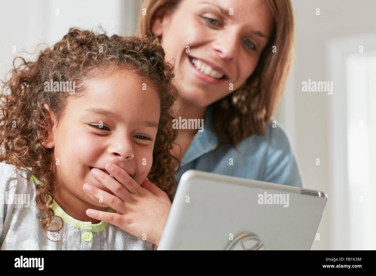 Niedrigen Winkel Ansicht von Mutter und Tochter mit digital-Tablette, mit der Hand über den Mund Lächeln Stockfoto