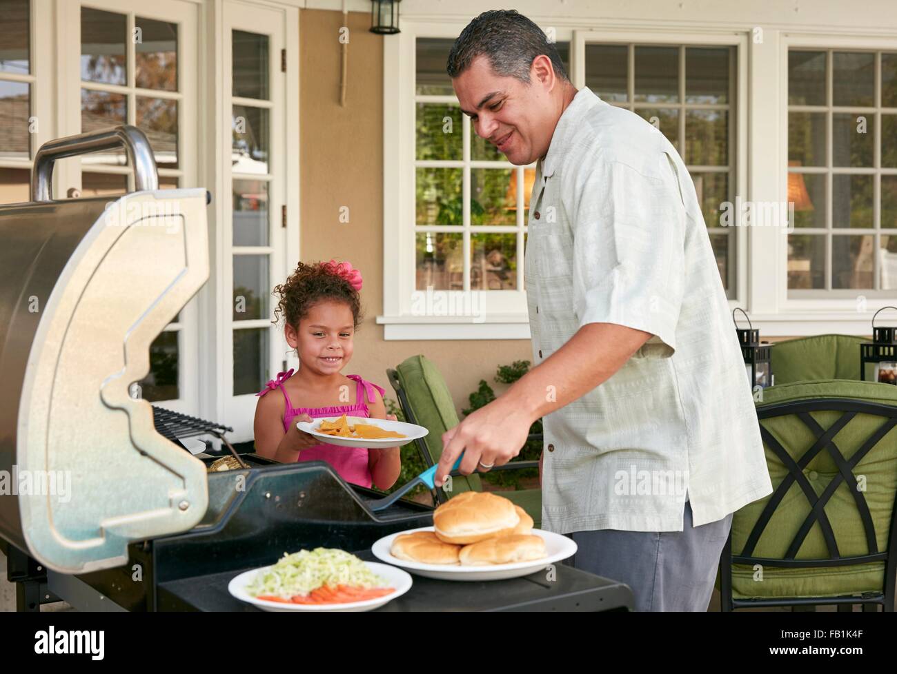 Vater und Tochter auf der Terrasse grillen Grill Essen Lächeln Stockfoto