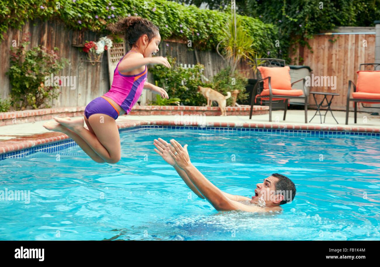 Seitenansicht des Vaters fangen Mädchen Sprung ins Schwimmbad, in der Luft Stockfoto