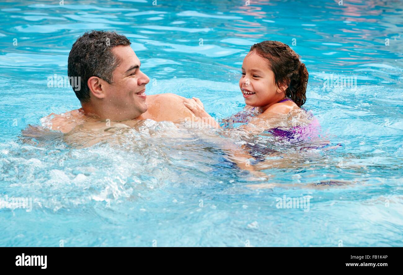 Kopf und Schultern von Vater und Tochter im Schwimmbad lächelnd Stockfoto