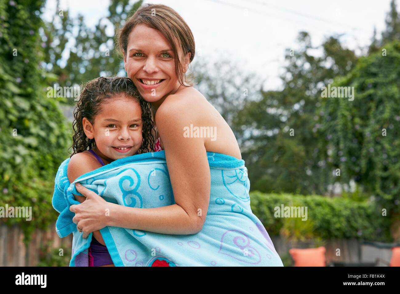 Mutter und Tochter, die das Tragen von Badebekleidung in Blick auf die Kamera zu Lächeln Handtuch gewickelt Stockfoto