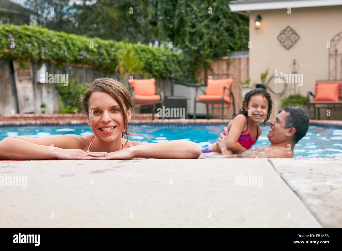 Kopf und Schultern Mitte erwachsenen Frau mit Familie im Pool mit Blick in die Kamera Lächeln Stockfoto