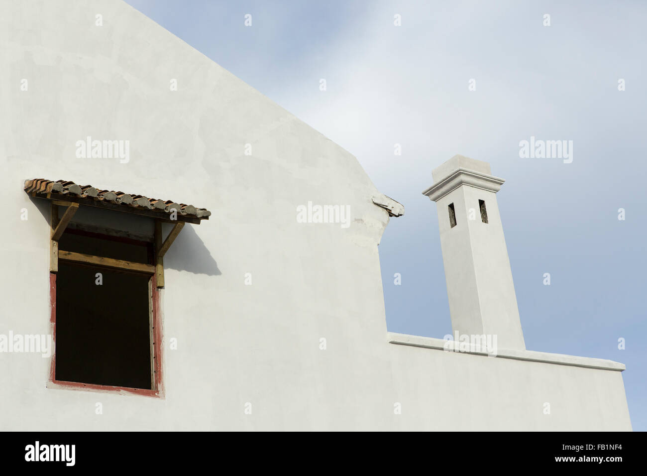Asiatische Architektur, Nahaufnahme eines Fensters mit Regenhaube und einem ungewöhnlichen Entlüfter oder Schornstein. Weiße Mauern umgebene Gebäude gegen blau Stockfoto