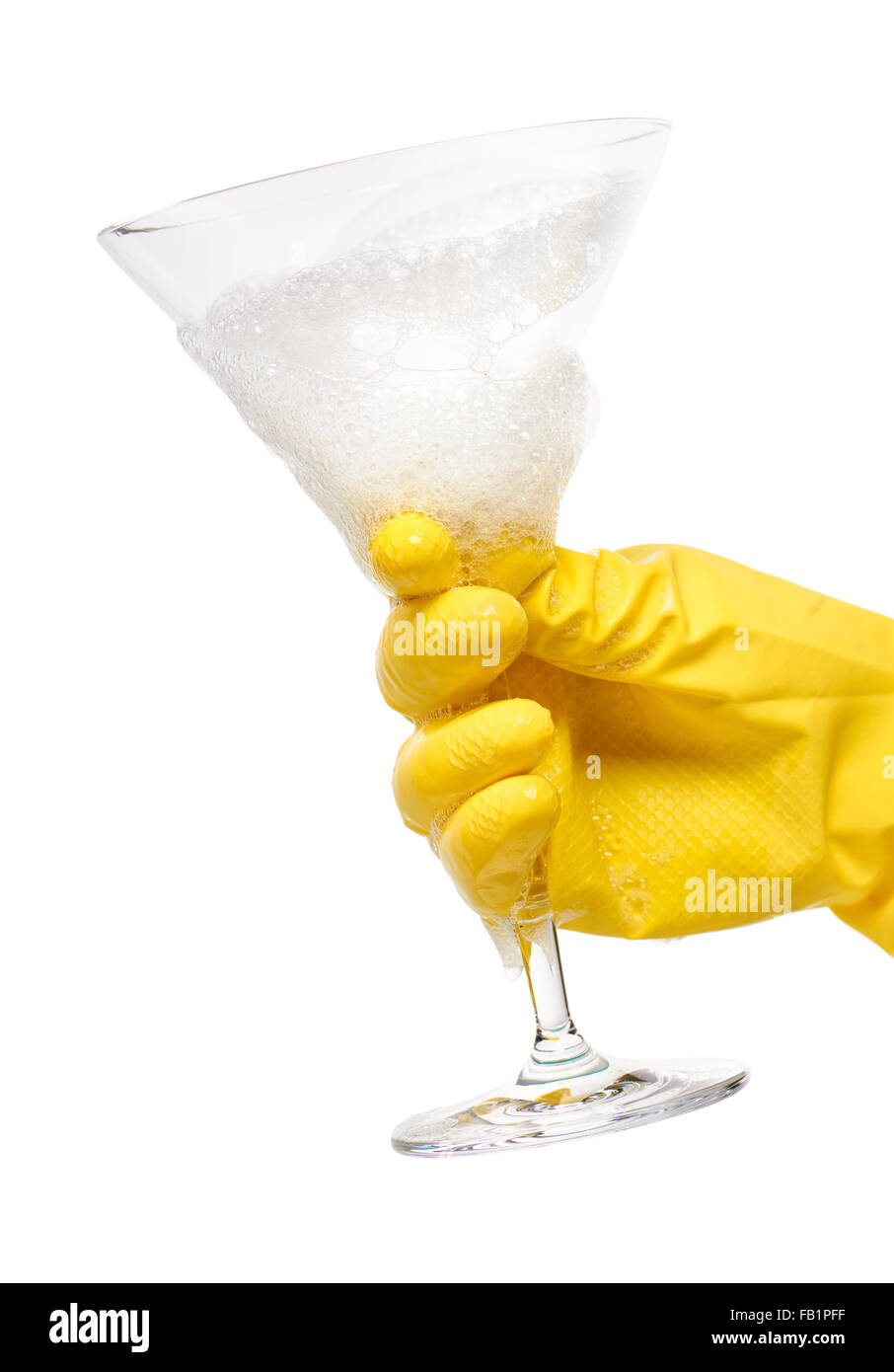 Nahaufnahme von weiblicher Hand in gelben schützende Gummihandschuh hält sauber transparent Martini-Glas in Schaum gegen weiß Stockfoto