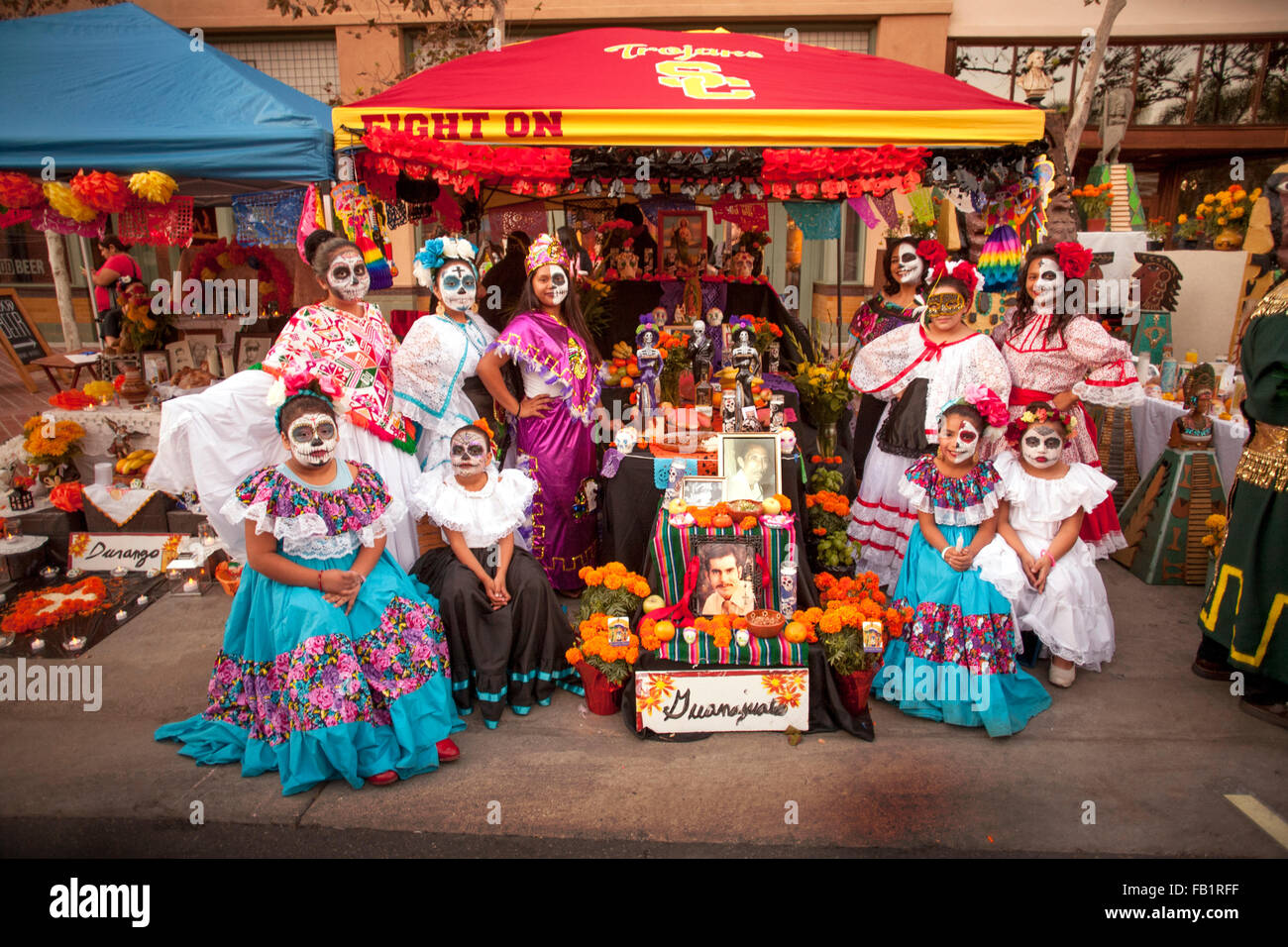 Geschminkt wie das Gesicht von La Calavera Catrina ("Dapper Skelett") Familienmitglieder stellen an einem Altar zu Ehren ein verstorbenes Verwandten im Laufe des Tages der Toten oder Dia de Muertos Urlaub unter Hispanics in Santa Ana, Kalifornien. Der Urlaub im Mittelpunkt Servi Stockfoto