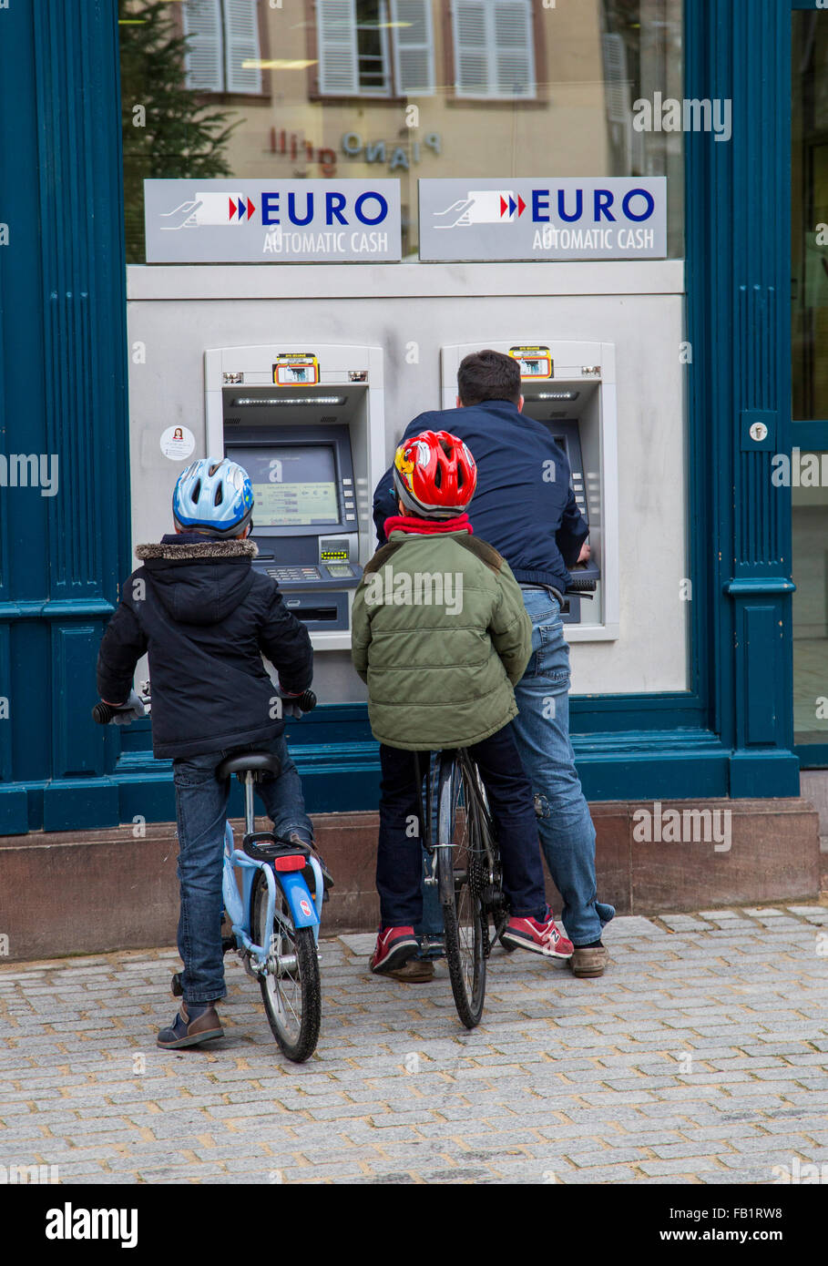 Person mit 2 Kindern an einem Bank-Automaten immer Geld Stockfoto
