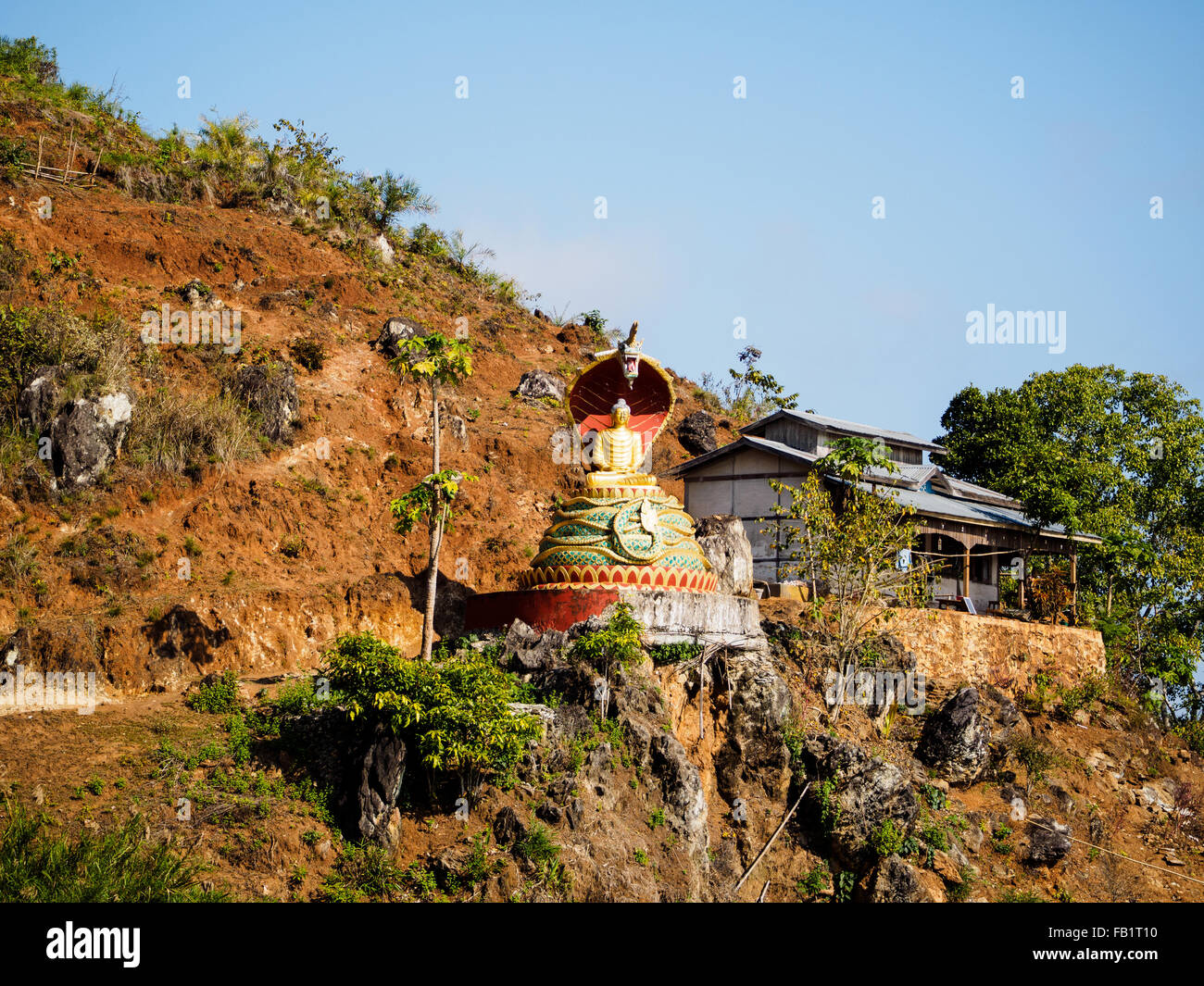 Eine Buddha-Statue sitzt unter dem Vordach der Kopf einer Schlange an der Klippe von Shwe Taung Tempel. Stockfoto