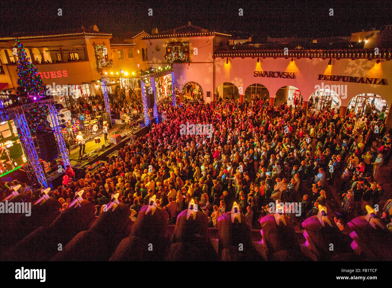 Umrahmt von Dachziegeln, besucht ein großes Publikum eine Nacht Zeit Weihnachtskonzert Rock ' n Roll in einem Einkaufszentrum San Clemente, Kalifornien. Hinweis Weihnachtsbaum auf der Bühne. Stockfoto