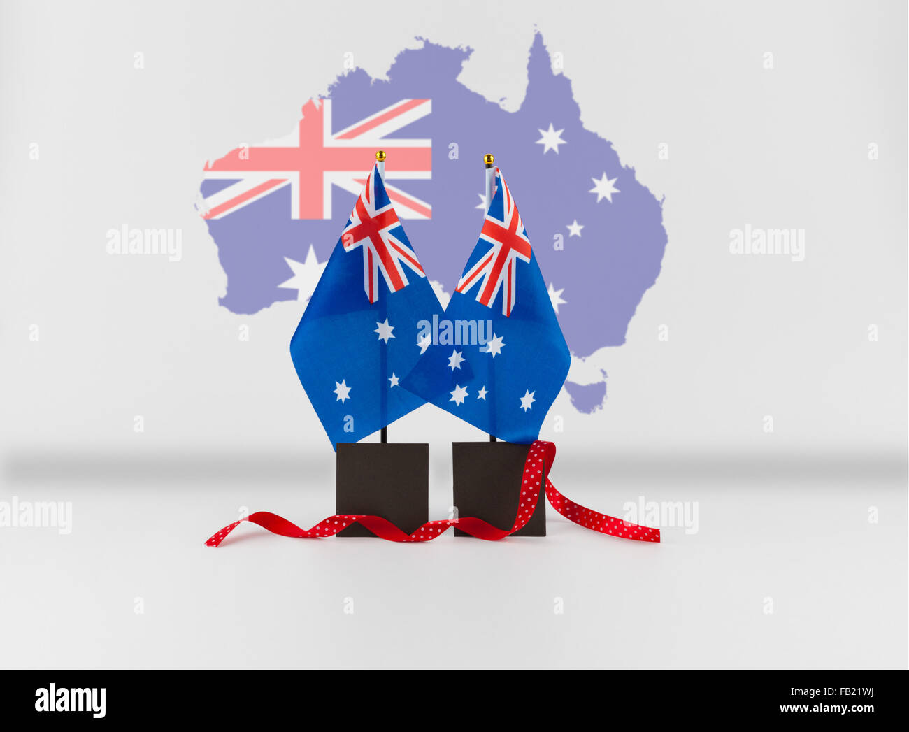 Zwei australische Schreibtisch Fahnen und roten Band mit Karte von Australien im Hintergrund und Kopie Raum. Australische nationale Symbole iso Stockfoto