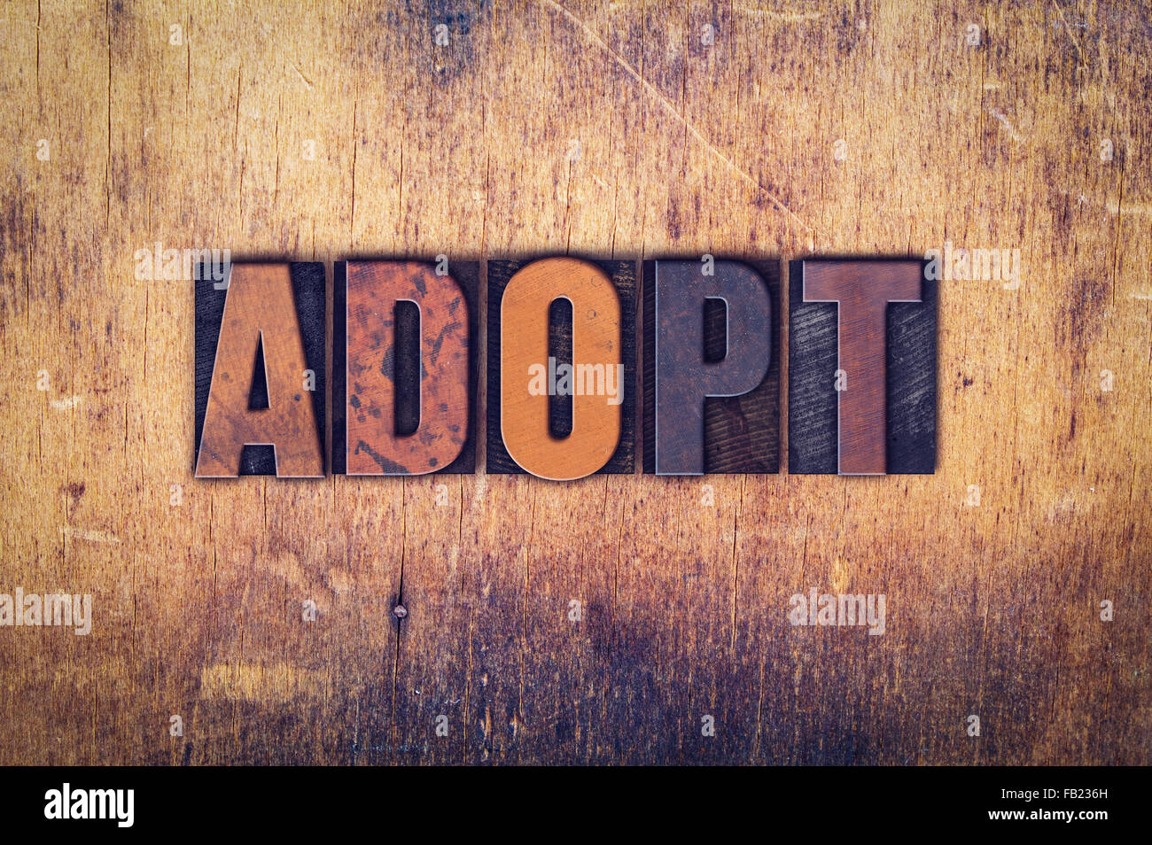 Das Wort "Adoptieren" in schmutzigen Vintage Buchdruck Typ auf einem alten hölzernen Hintergrund geschrieben. Stockfoto
