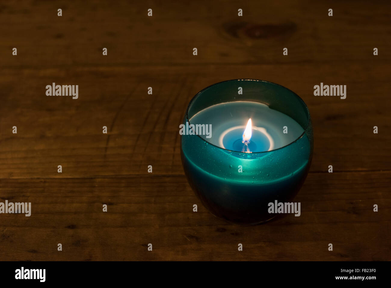 Blaue Kerze beleuchtet auf einem Holztisch Stockfoto