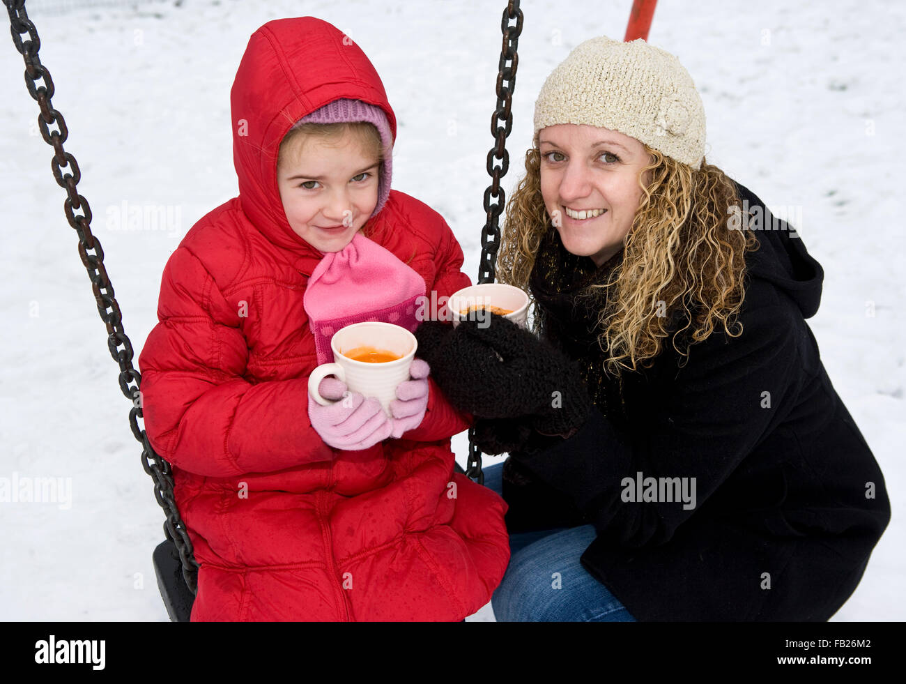 Junges Mädchen mit Mama im Schnee trinken warmen Tomatensuppe eingehüllt in warme Decken Stockfoto