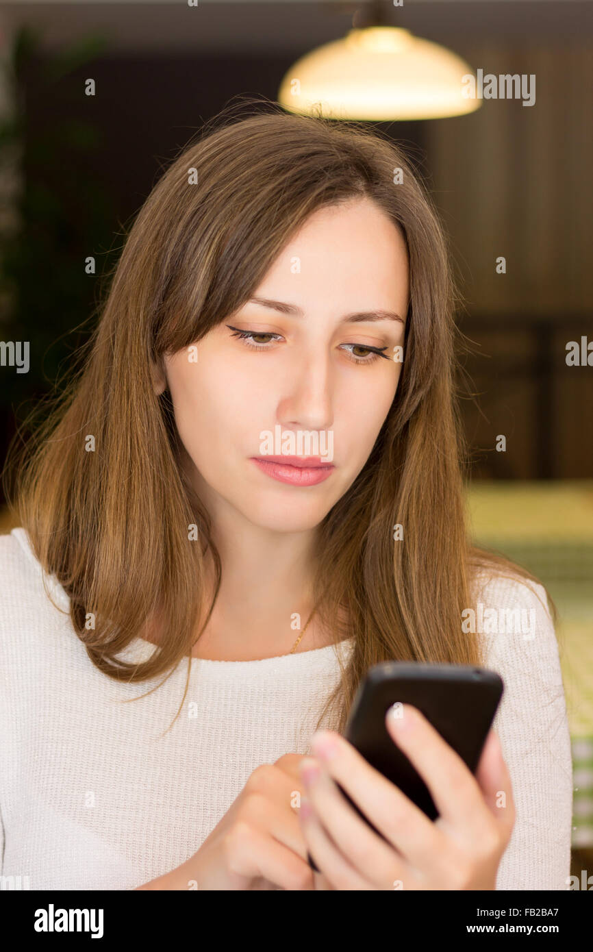 Schöne junge Frau mit ihrem Smartphone im Café. Kaukasische Dame im Restaurant testen Stockfoto