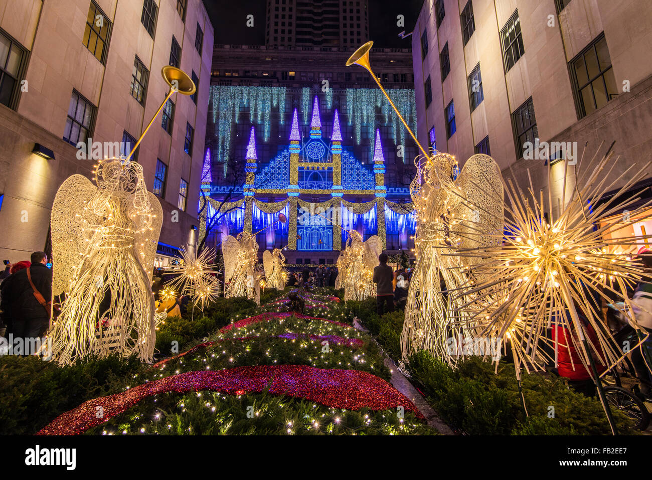 Weihnachtsengel im Rockefeller Center Channel Gardens mit Saks Kaufhaus Christmas Light Show hinter New York, USA Stockfoto