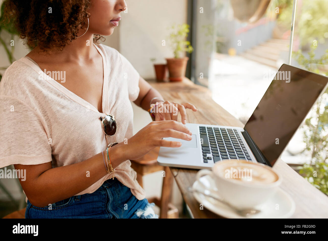 Bild der jungen Frau, die Arbeiten am Laptop sitzen im Café beschnitten. Afrikanisches Mädchen mit Laptop-Computer mit einer Tasse Kaffee auf Stockfoto