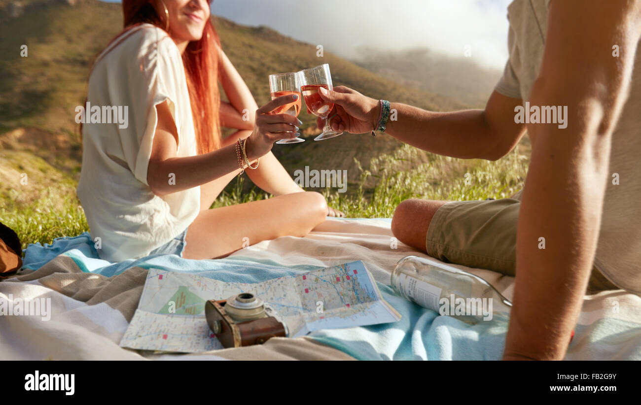 Schuss von Mann und Frau Toasten Wein unterwegs ein Picknick beschnitten. Junges Paar genießen ein Picknick im Freien mit Wein auf einem Sommer-d Stockfoto