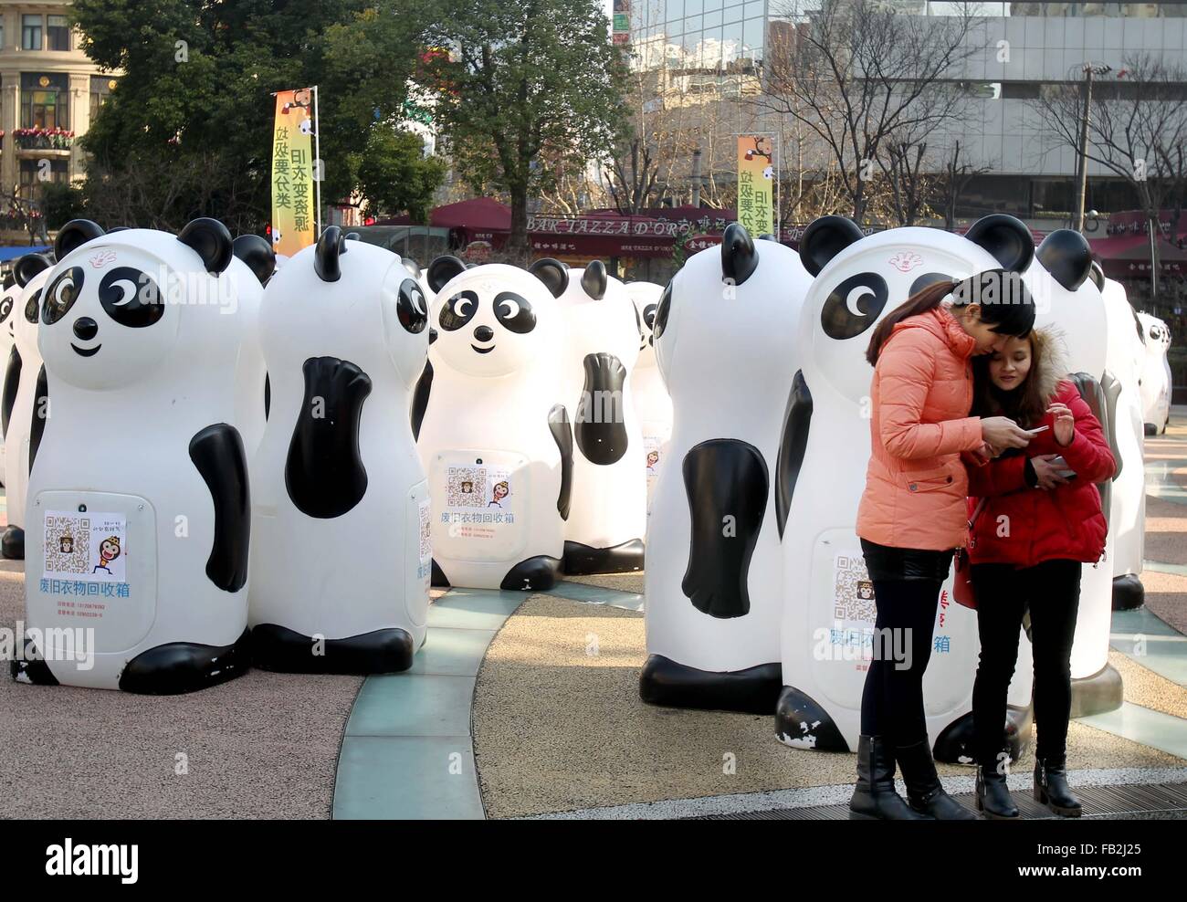 Shanghai, China. 8. Januar 2016. Menschen überprüfen Sie Fotos vor dem Panda-Stil recycling-Behälter in Shanghai, Ost-China, 8. Januar 2016. Insgesamt 800 Panda-Stil recycling-Behälter Auftritt auf Shiji Square in Nanjing Road zu Fuß Straße und in Huaihai Park am Freitag gemacht, auf alte Kleidung und Schuhe etc. gefüttert. Recyceltes Material in guter Qualität werden nach der Reinigung auf die benötigten gespendet. Bildnachweis: Liu Ying/Xinhua/Alamy Live-Nachrichten Stockfoto
