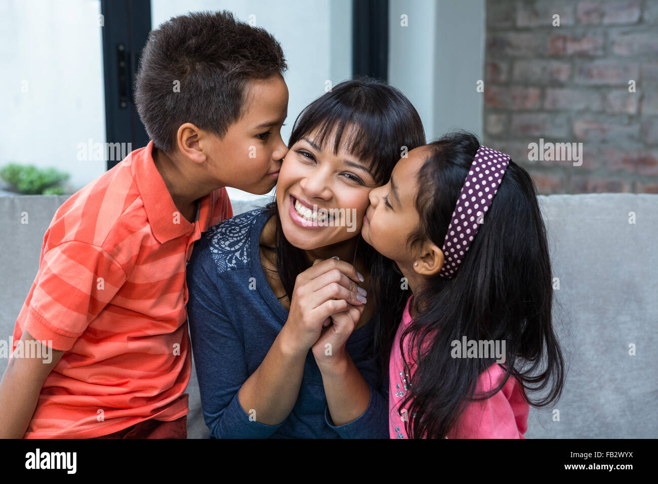 Glückliche Mutter von ihren Kindern geküsst werden Stockfoto