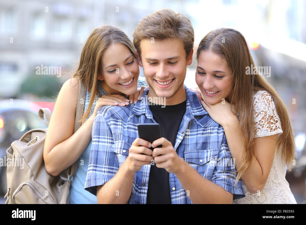 Lustige Freunde freigeben von Medien in ein Smartphone in der Straße Stockfoto