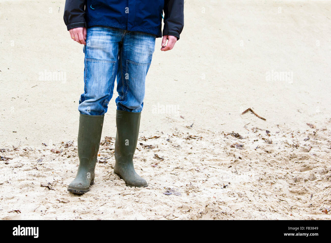 Mann trägt Gummistiefel und im Sand stehen Stockfoto