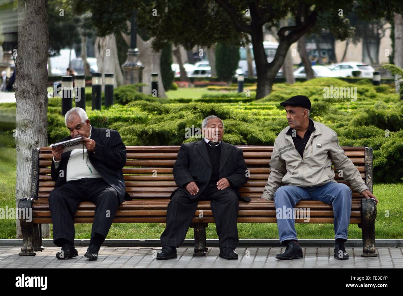 BAKU, Aserbaidschan - 26. April 2014 aserbaidschanischen Männer draußen sitzen und sprechen über Baku Bulvar. Drei Männer im Gespräch auf einer Bank Stockfoto