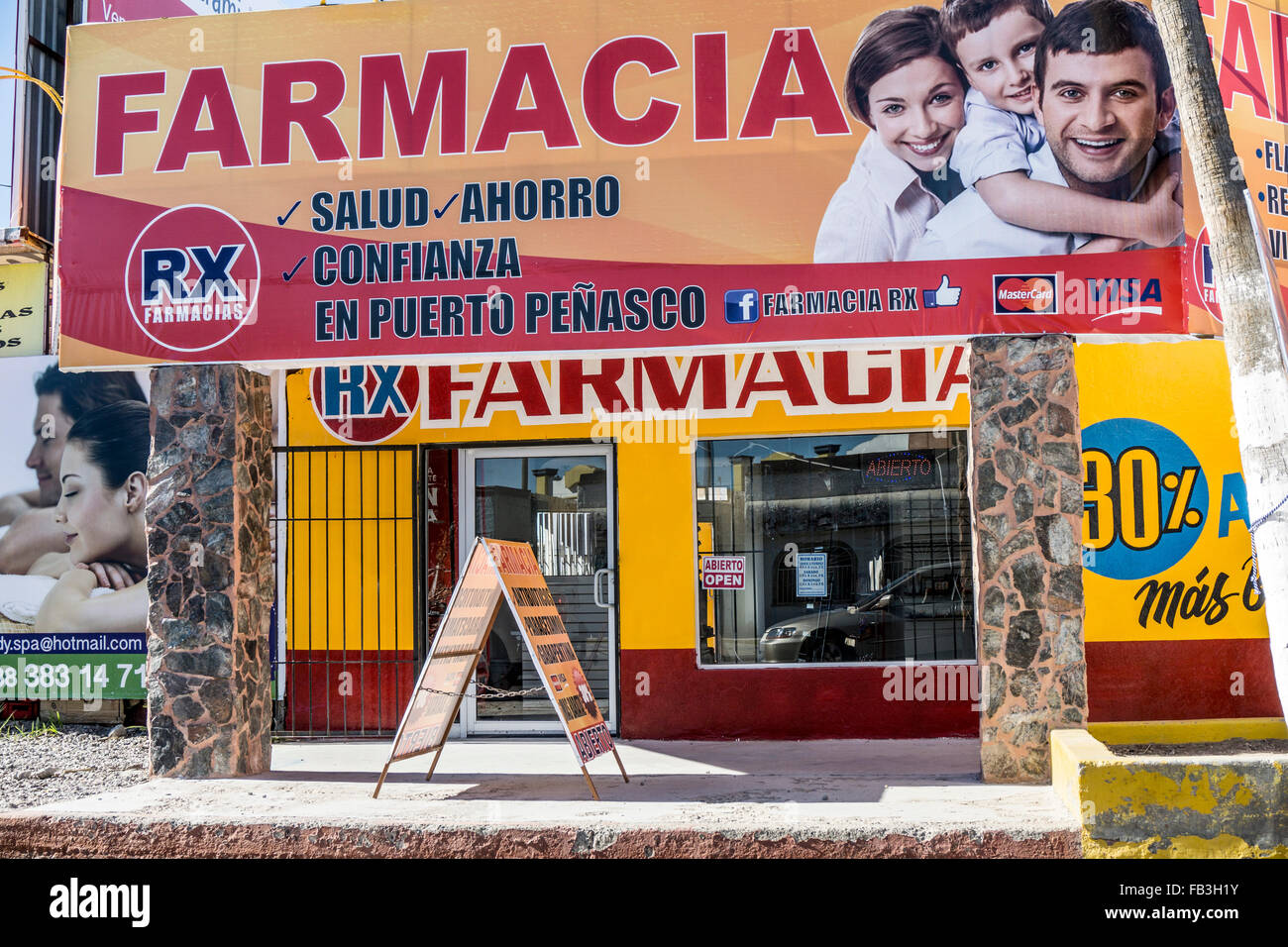 Vorderseite der Apotheke gemalt hellgelb & Pflaume & übergestiegen durch riesige reißerische Werbung Billboard auf Hauptstraße Puerto Penasco Stockfoto