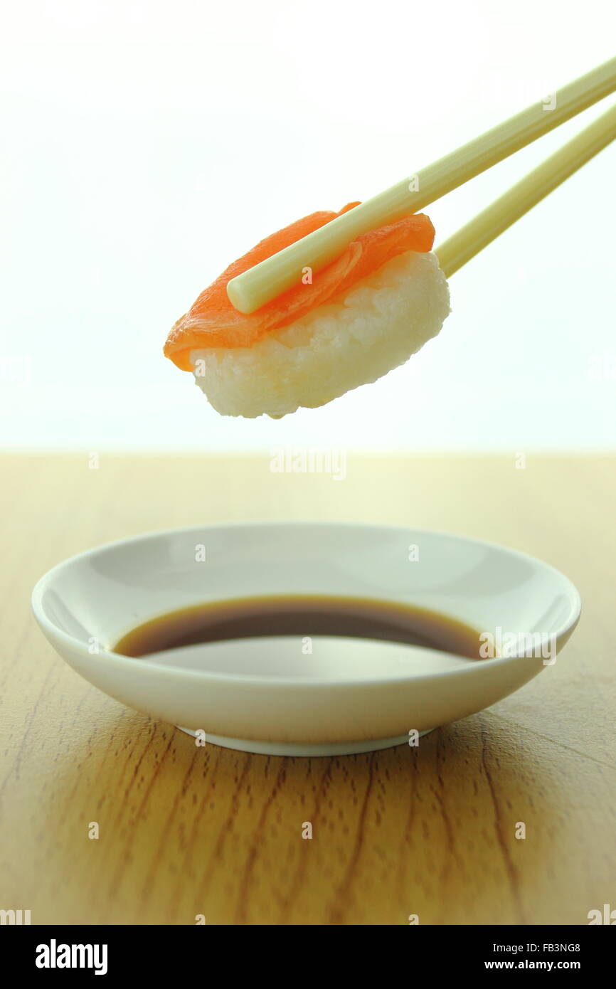 Holding-Lachs Sushi-Rolle mit Stäbchen und Shoyu-sauce Stockfoto