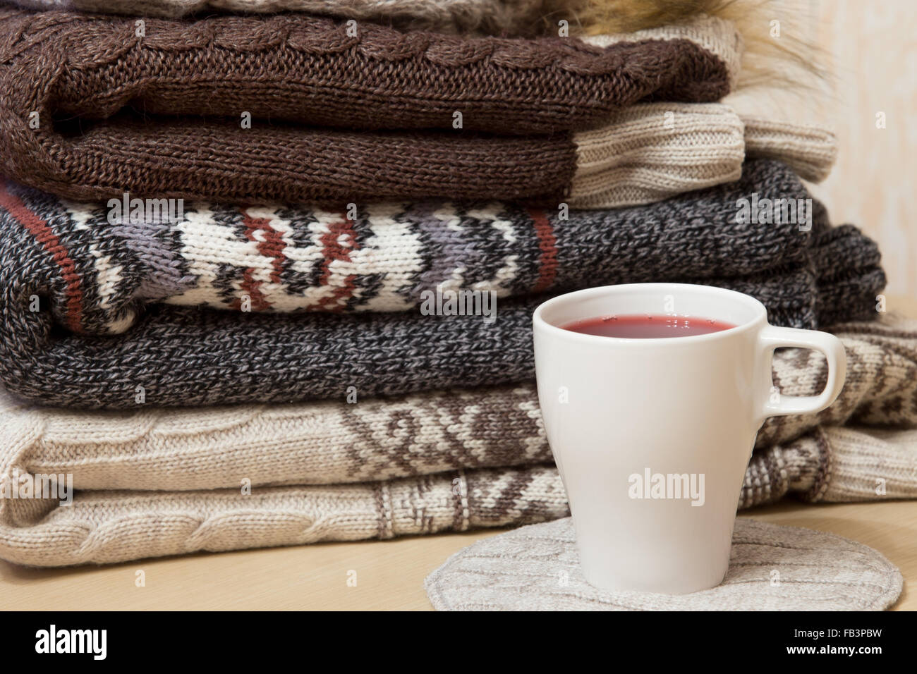 Haufen von gefalteten Winter Pullover und weiße Tasse Glühwein Stockfoto