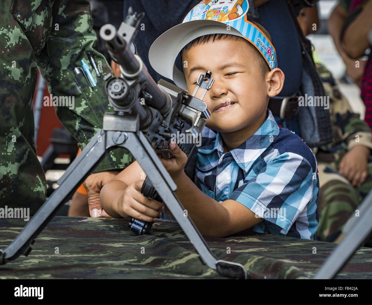 Bangkok, Thailand. 9. Januar 2016. Ein Thai junge spielt mit einem Maschinengewehr Armee während der Kinder Tag Festlichkeiten in der Royal Thai Army Palastwache, 2. Division Kavallerie Basis in Bangkok. Nationaler Kindertag fällt am zweiten Samstag des Jahres. Thailändische Regierungsagenturen Kind freundlich Events sponsern und das Militär in der Regel öffnet Militärbasen für Kinder, die kommen, um auf Panzer und Artilleriestücke spielen. Bildnachweis: Jack Kurtz/ZUMA Draht/Alamy Live-Nachrichten Stockfoto