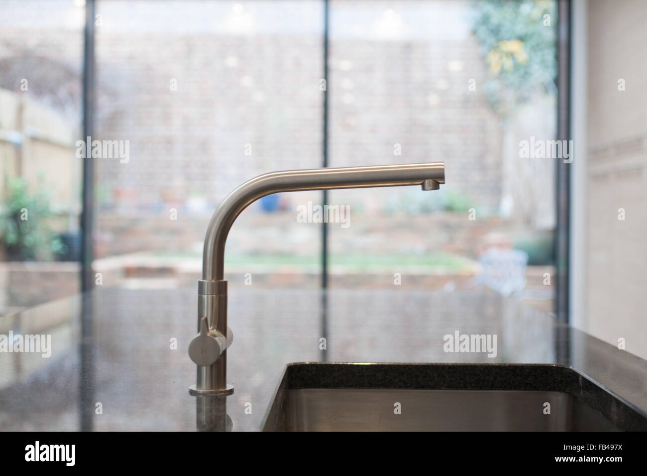 Wasserhahn, Waschbecken und Garten Türen in modernen Küche Stockfoto